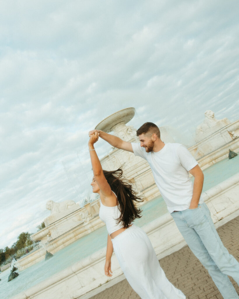 Man twirling his fiancé during their downtown engagement shoot at Belle Isle