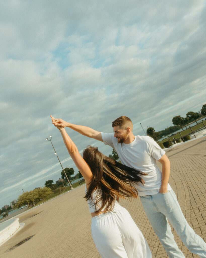 Man twirling his fiancé during their downtown engagement shoot at Belle Isle