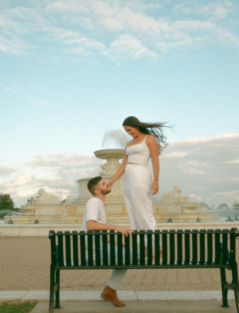 Couple posing for their downtown Detroit engagement photos at Belle Isle on a bench