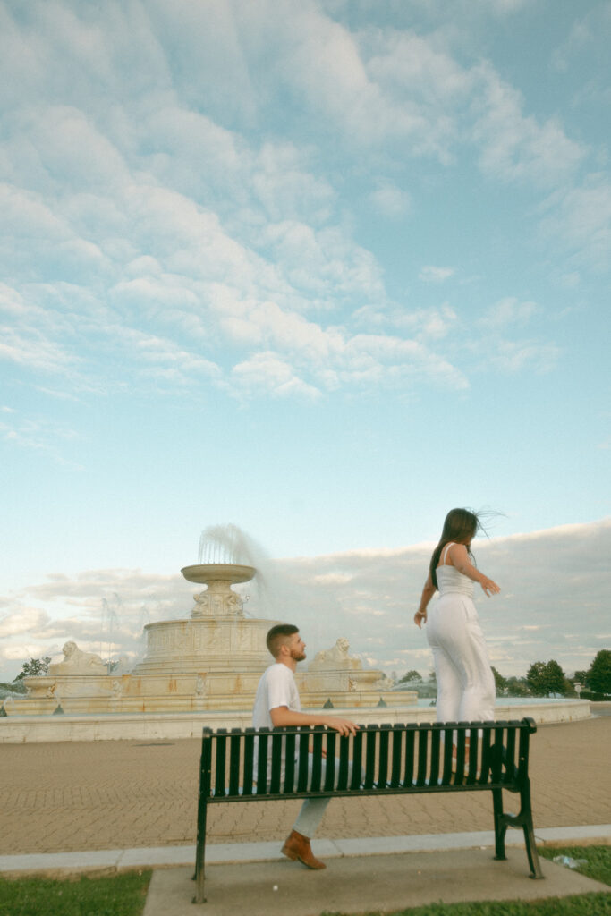 Couple posing for their downtown Detroit engagement photos at Belle Isle on a bench