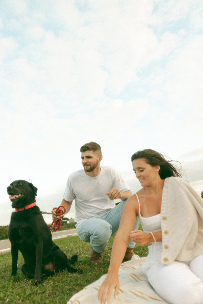 Couple sitting in the grass with their dog at Belle Isle in Detroit, MI