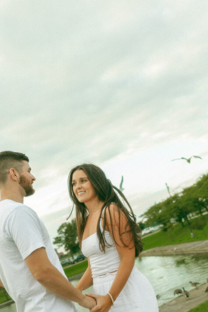 Couple holding hands during their windy engagement photos at Belle Isle