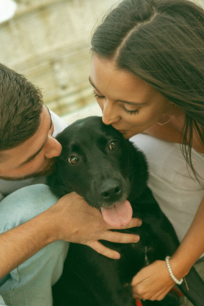 Man and woman kissing their dog during their engagement session