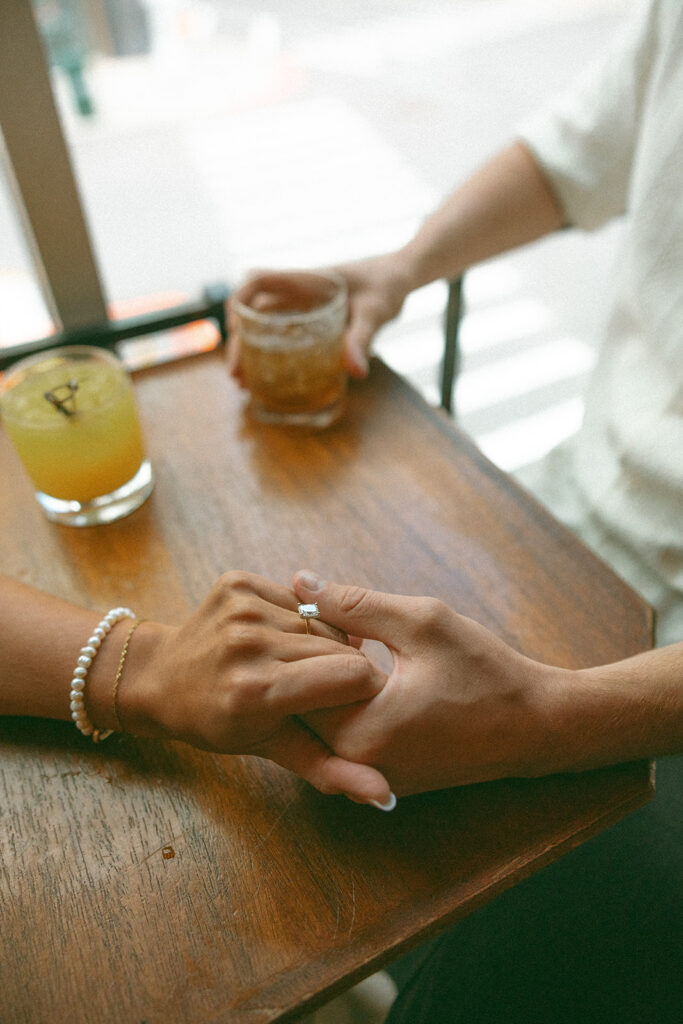 Couple holding hands during their bar engagement shoot