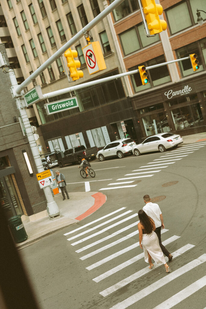 Couple walking across the street for their downtown engagement photos in Detroit, Michigan