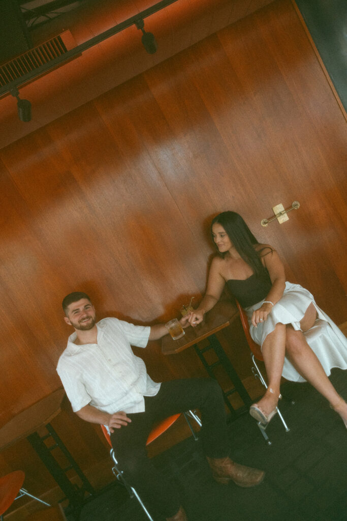 Couple holding hands during their bar engagement shoot