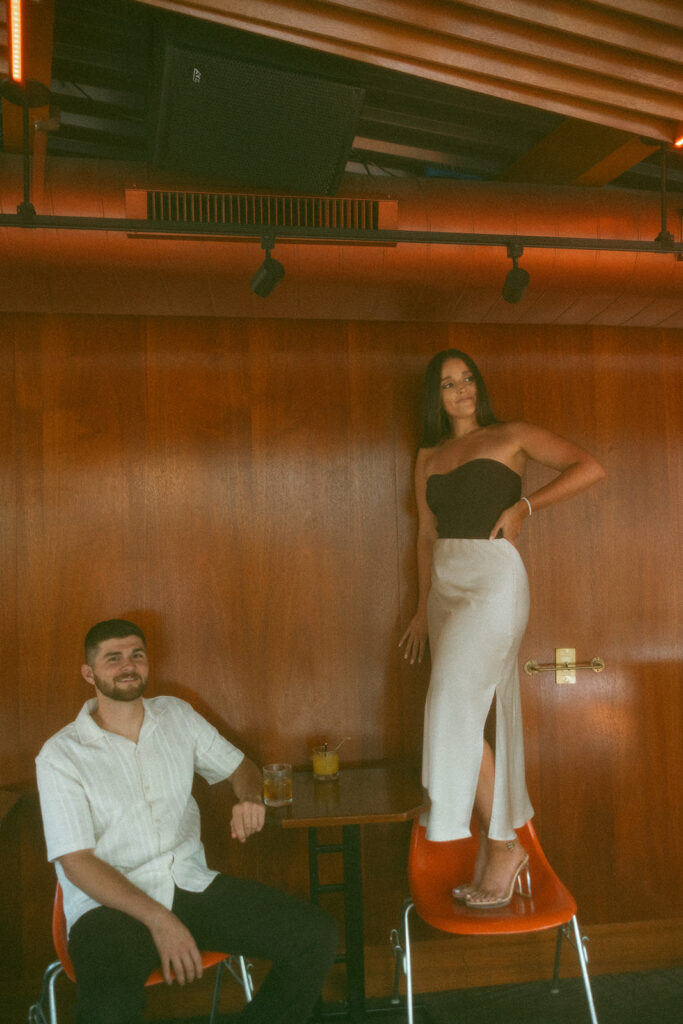 Couple posing in an editorial way for their downtown Detroit engagement photos at a bar