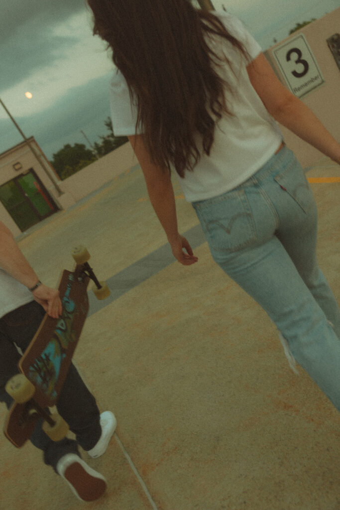 Couple going to longboard on a parking garage