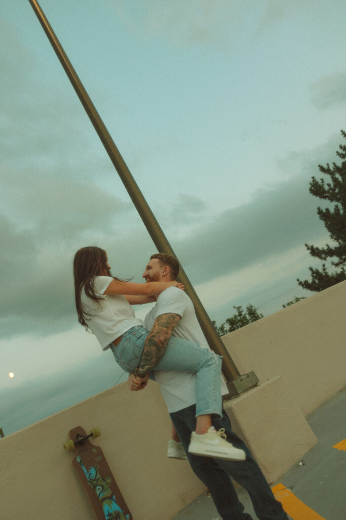 Man picking up his fiancé during their rooftop engagement shoot