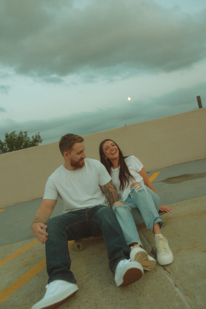 Couple sitting on a rooftop parking garage for their Midland engagement photos