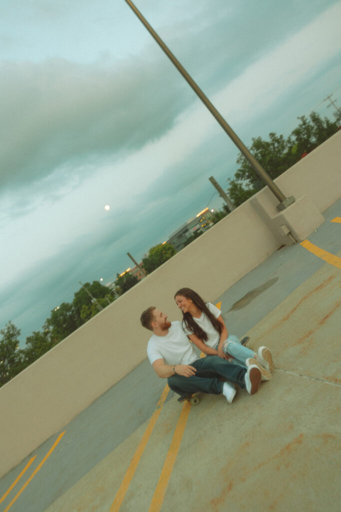 Couple sitting on a rooftop parking garage for their Midland engagement photos