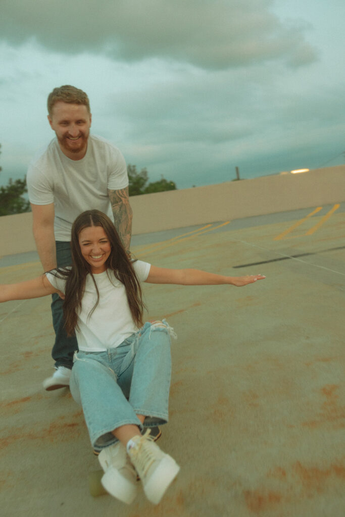 Man helping his fiancé while she sits on a longboard