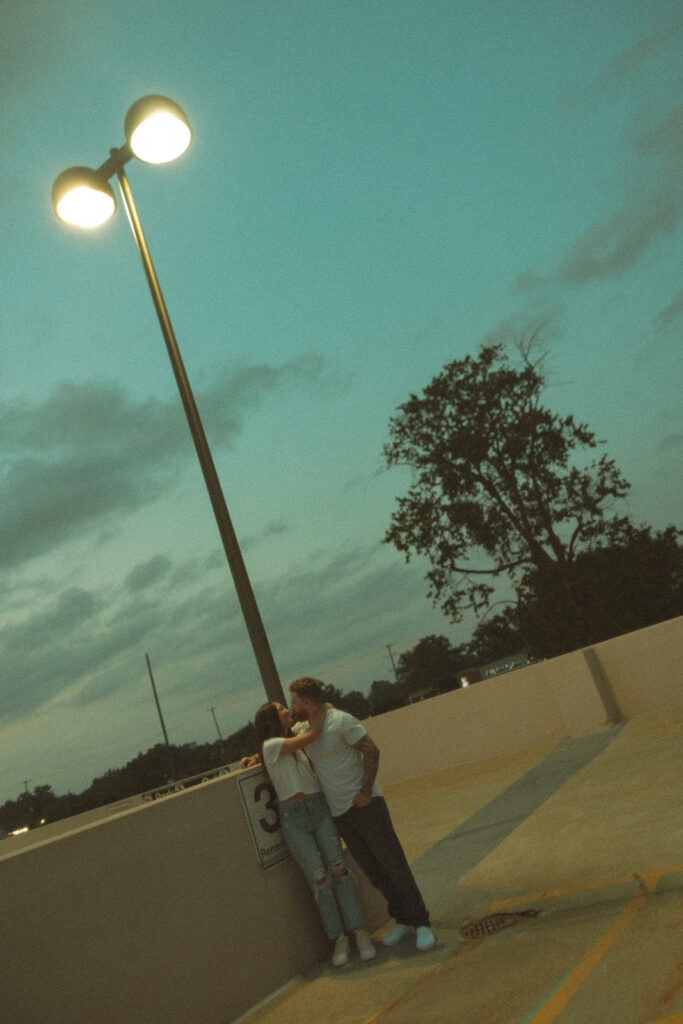 Couple posing underneath a streetlight during their Midland engagement photos