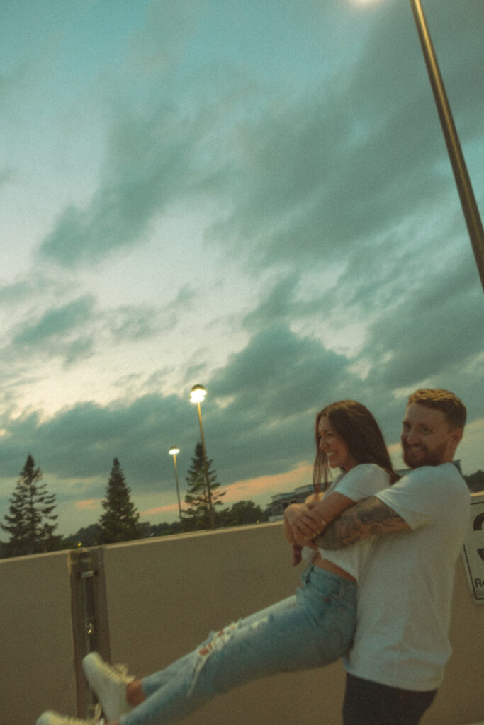 Man picking up his fiancé during their rooftop engagement session in Midland