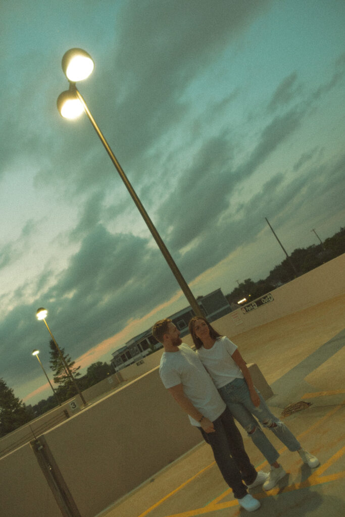 Couple posing on a rooftop parking garage at night