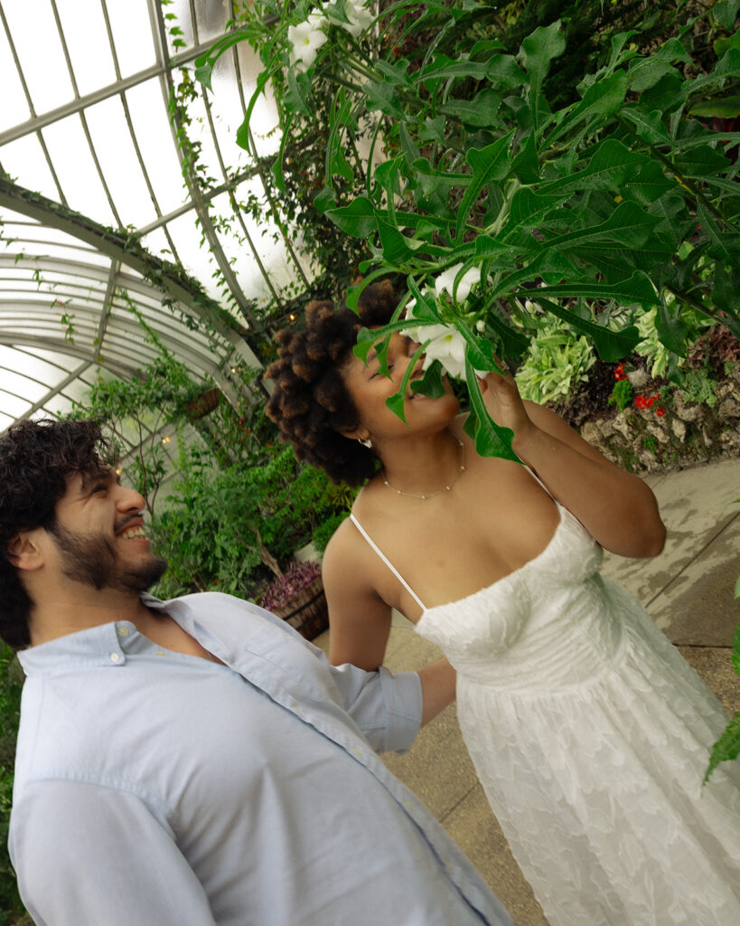 Couple admiring the flowers at The Conservatory at Belle Isle for their Detroit engagement photos.