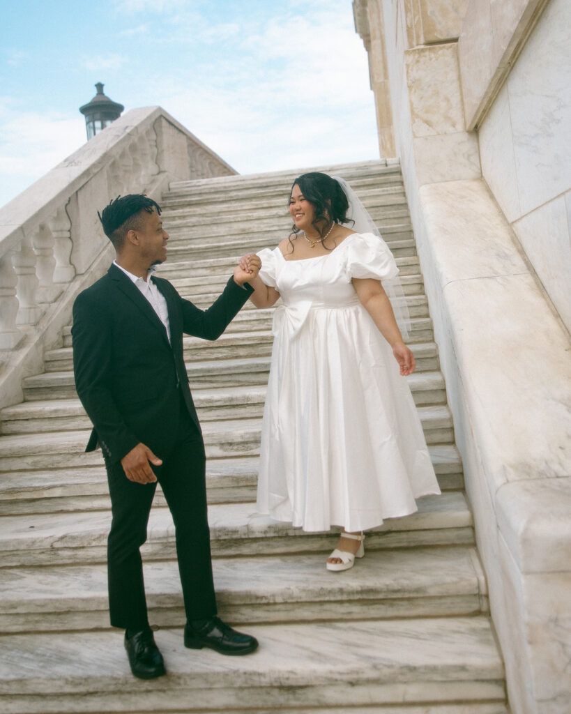 Man helping his bride walk down the stairs at Detroit Institute of Arts.