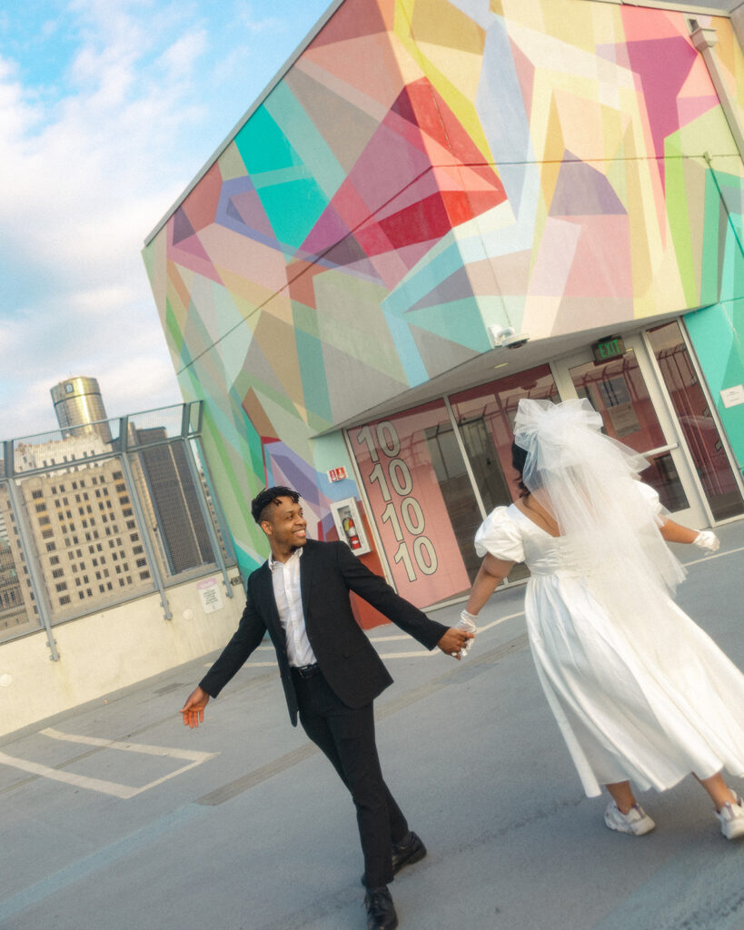 Couple walking up on Z Lot in Detroit, Michigan in front of a colorful mural.