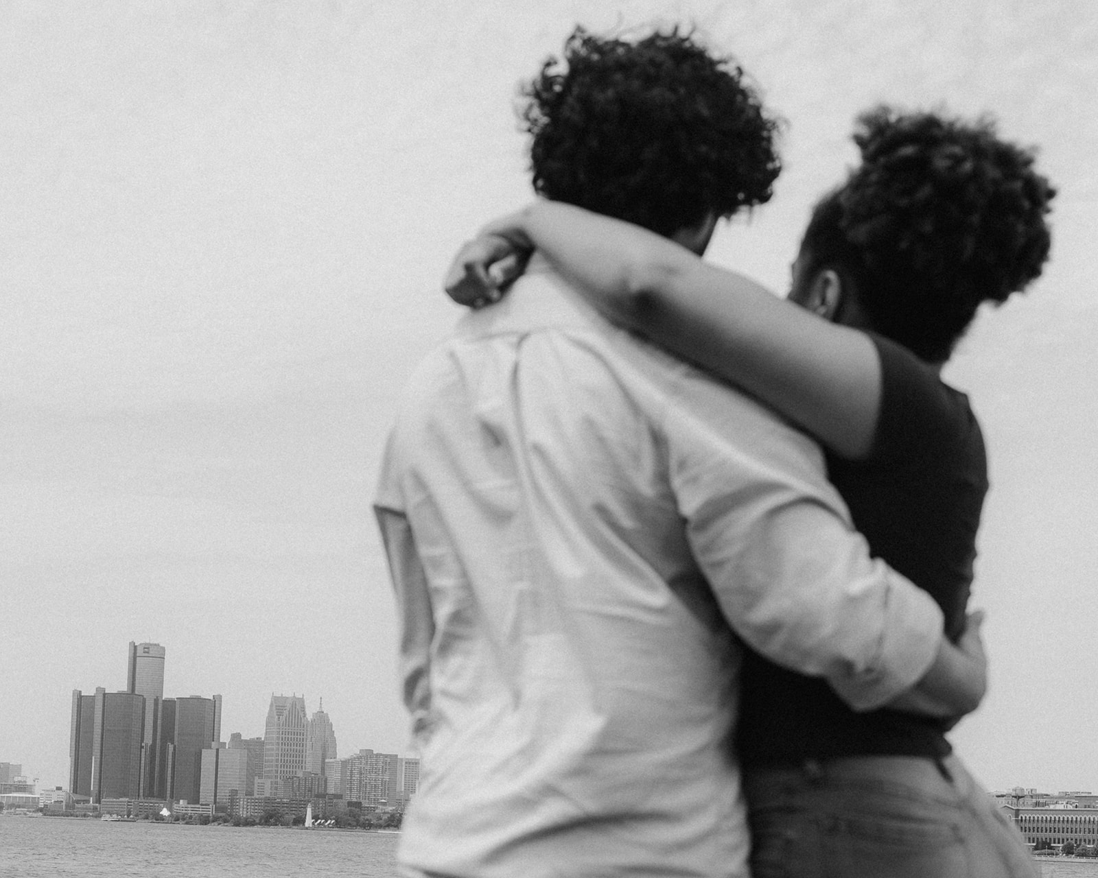 Black and white photo of a couple admiring the Detroit skyline during their engagement photos at Belle Isle.