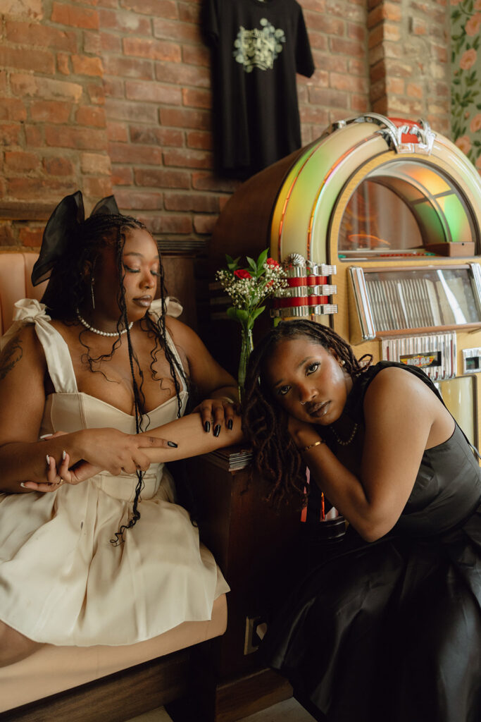 Couple sitting next to a juke box during their Detroit engagement photos at Time Will Tell.