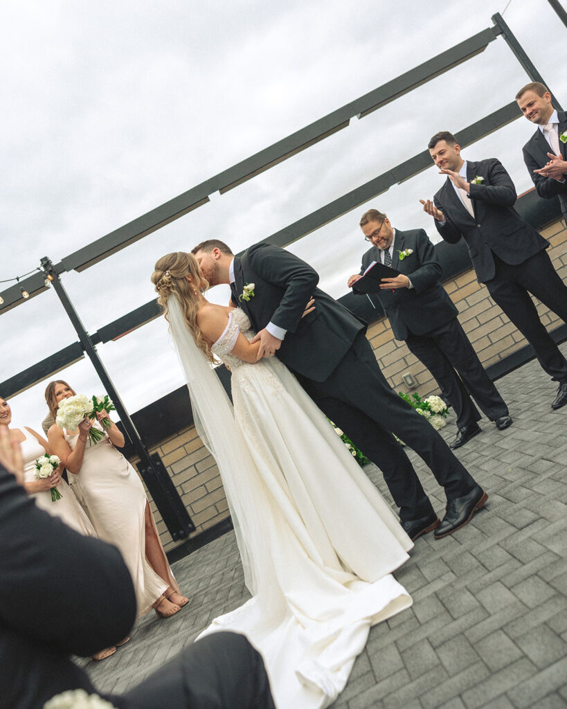 Bride and groom kissing during their rooftop patio wedding ceremony at Port 393 in Holland, Michigan.