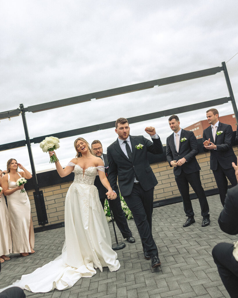 Bride and groom walking back down the aisle as husband and wife after their rooftop patio wedding ceremony at Port 393 in Holland, Michigan.