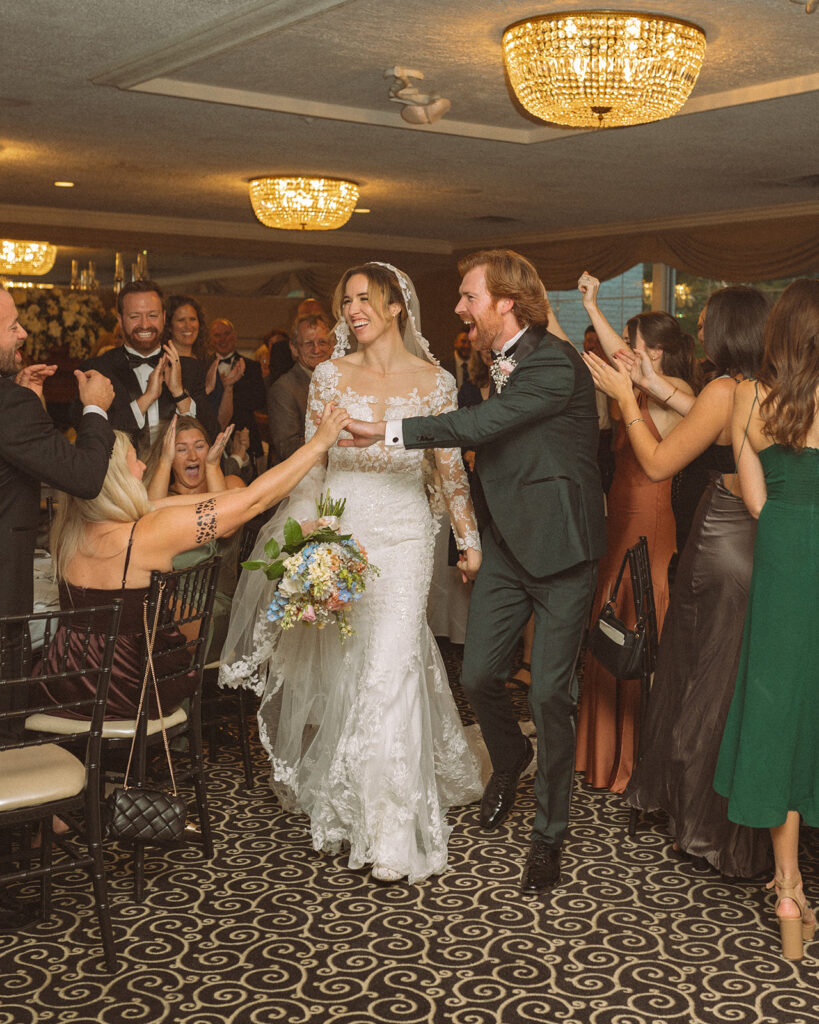 Newlyweds make their grand entrance to the reception greeted by excited guests