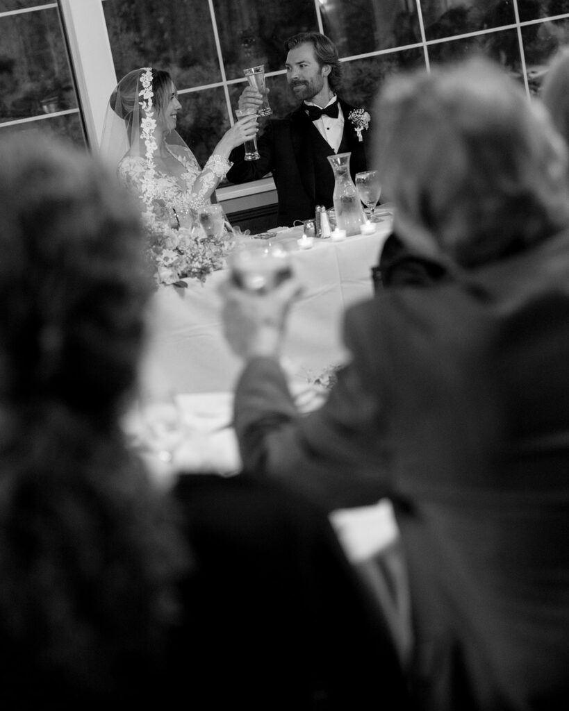 Couple raises glasses for a toast at their sweetheart table during Pine Knob Mansion wedding
