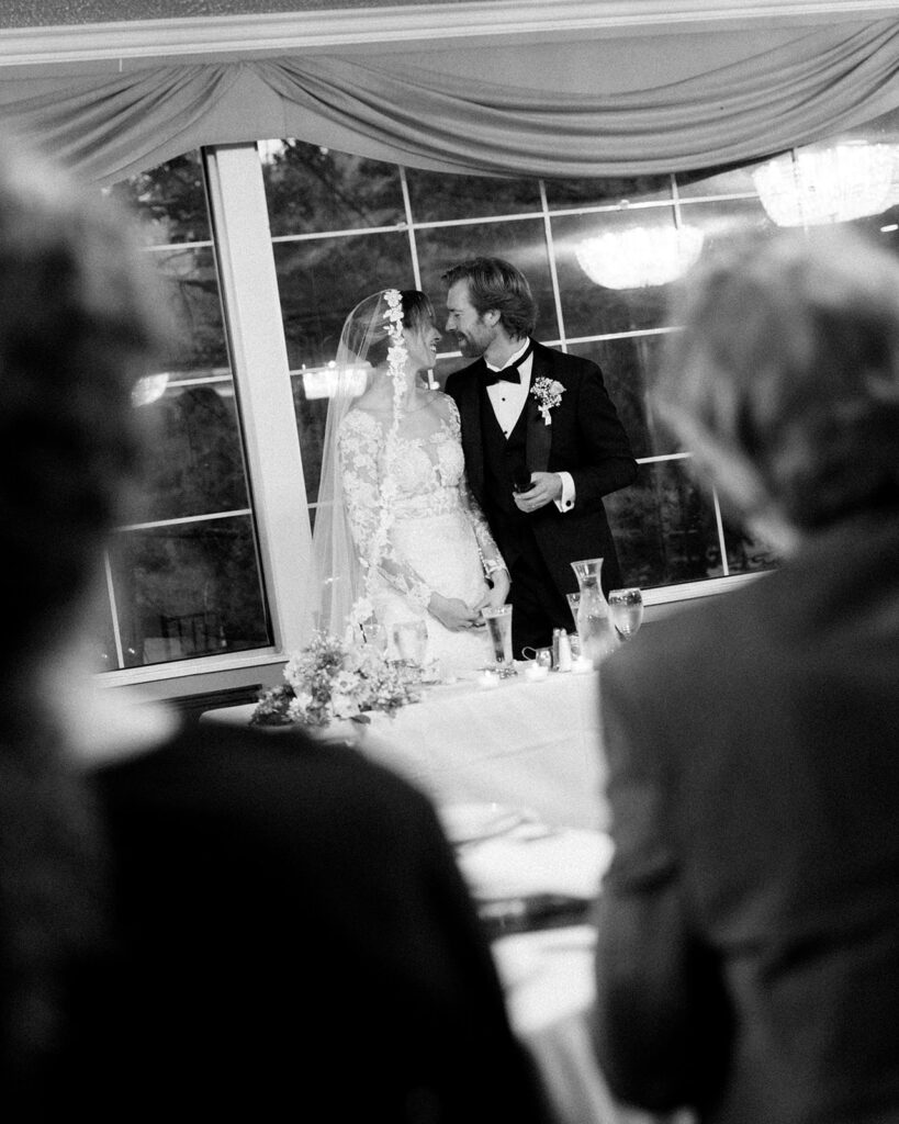 Couple shares a sweet moment after giving their speech, surrounded by guests at Pine Knob Mansion wedding reception