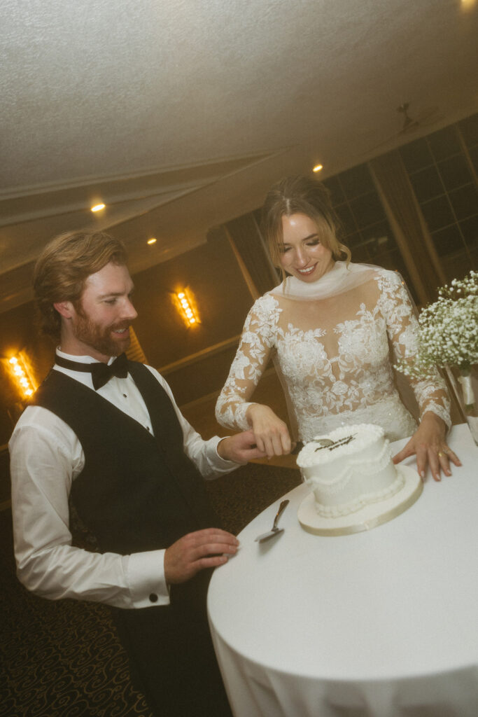 Bride and groom cut into their wedding cake during fun and candid reception moment