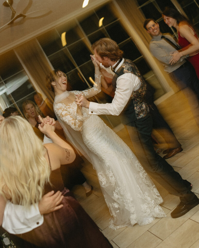 Bride and groom dancing and laughing together during their wedding reception at Pine Knob Mansion