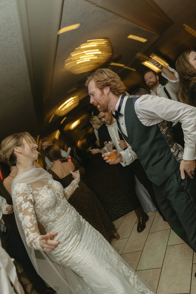 Bride and groom dancing among guests under chandeliers at Pine Knob Mansion