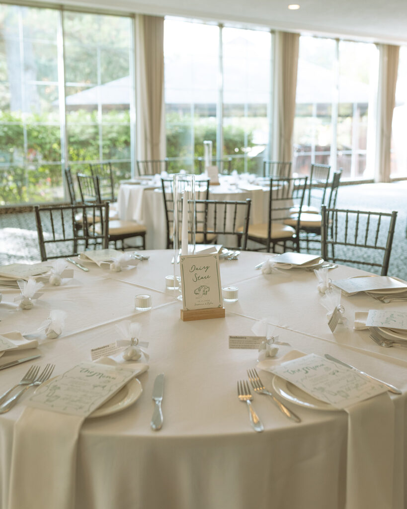 Minimalist wedding table setting with white linens and elegant stationery inside Pine Knob Mansion wedding reception