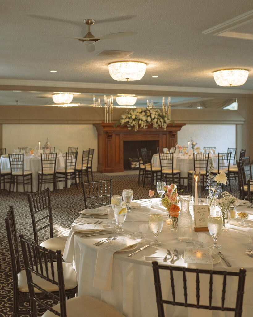 Wide view of the formal reception room with round tables and chandeliers at Pine Knob Mansion