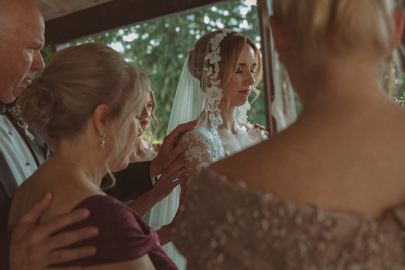 Family praying during a Pine Knob Mansion wedding ceremony in the Carriage House