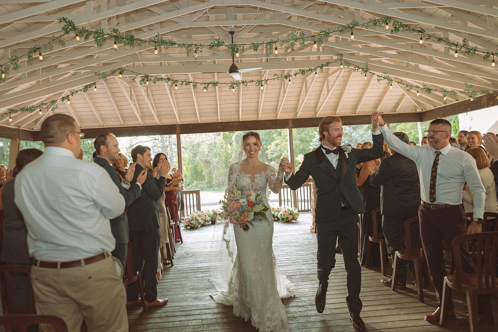 Bride and groom walking back down the aisle as husband and wife after their Pine Knob Mansion wedding ceremony in the Carriage House