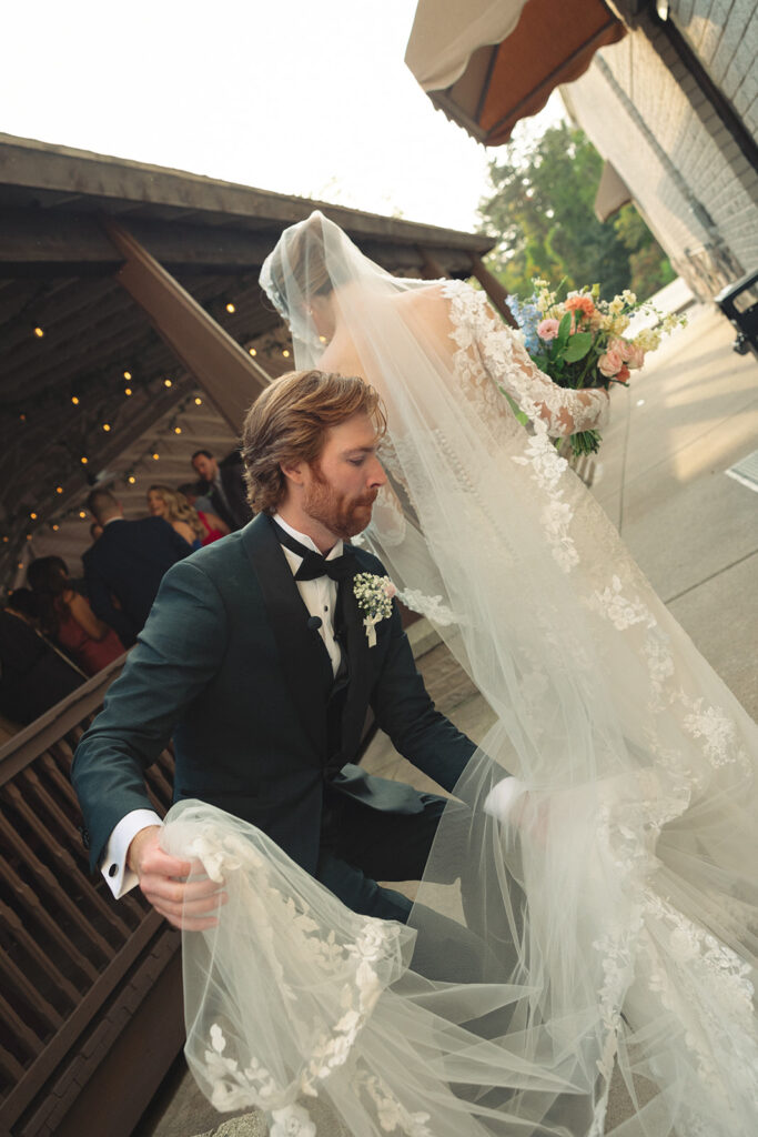 Candid Detroit wedding photo of a groom adjusting his brides veil and trail