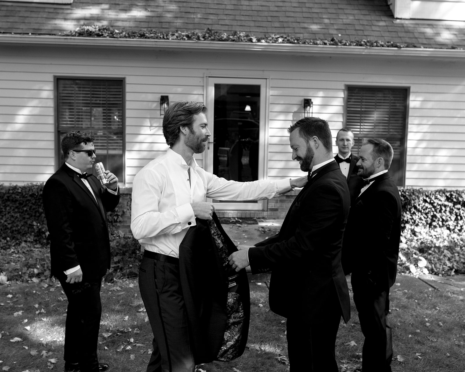Black and white candid photo of a groom getting ready with his groomsmen