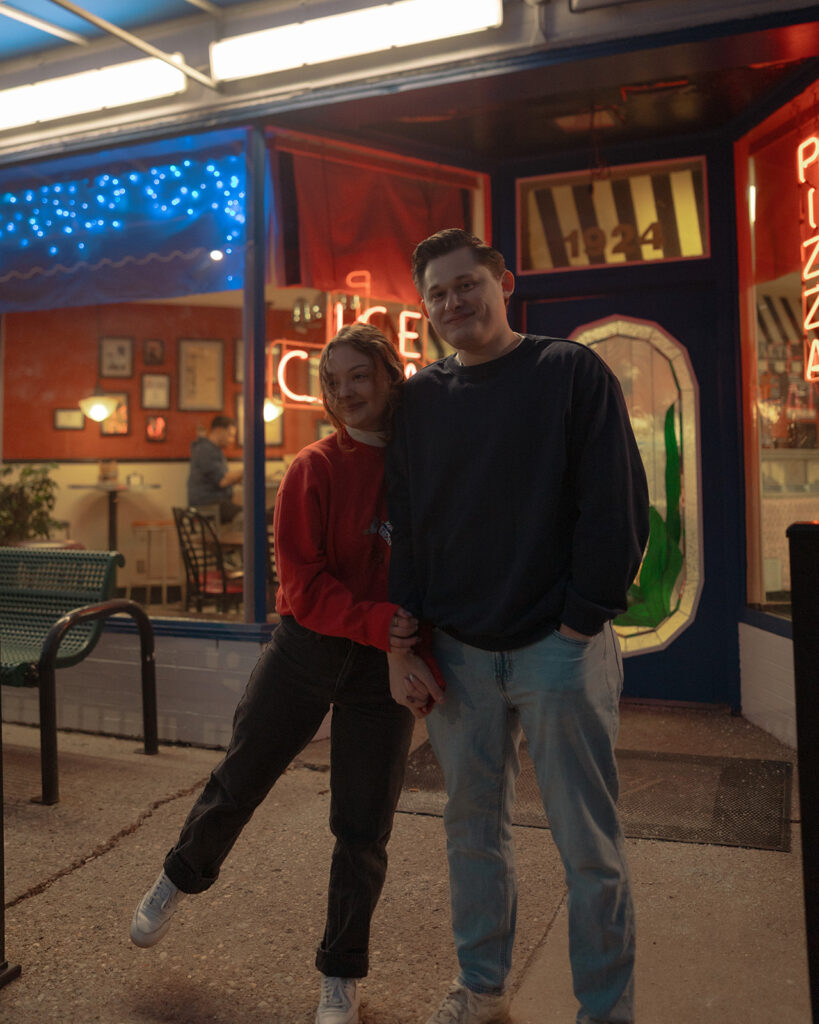 Couple posing outside of a Michigan ice cream shop for their engagement session