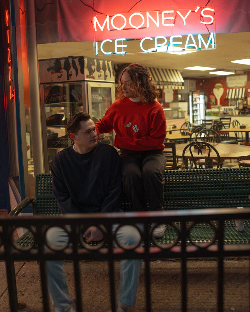 Couple posing outside of Mooney's Ice Cream for their Michigan engagement shoot