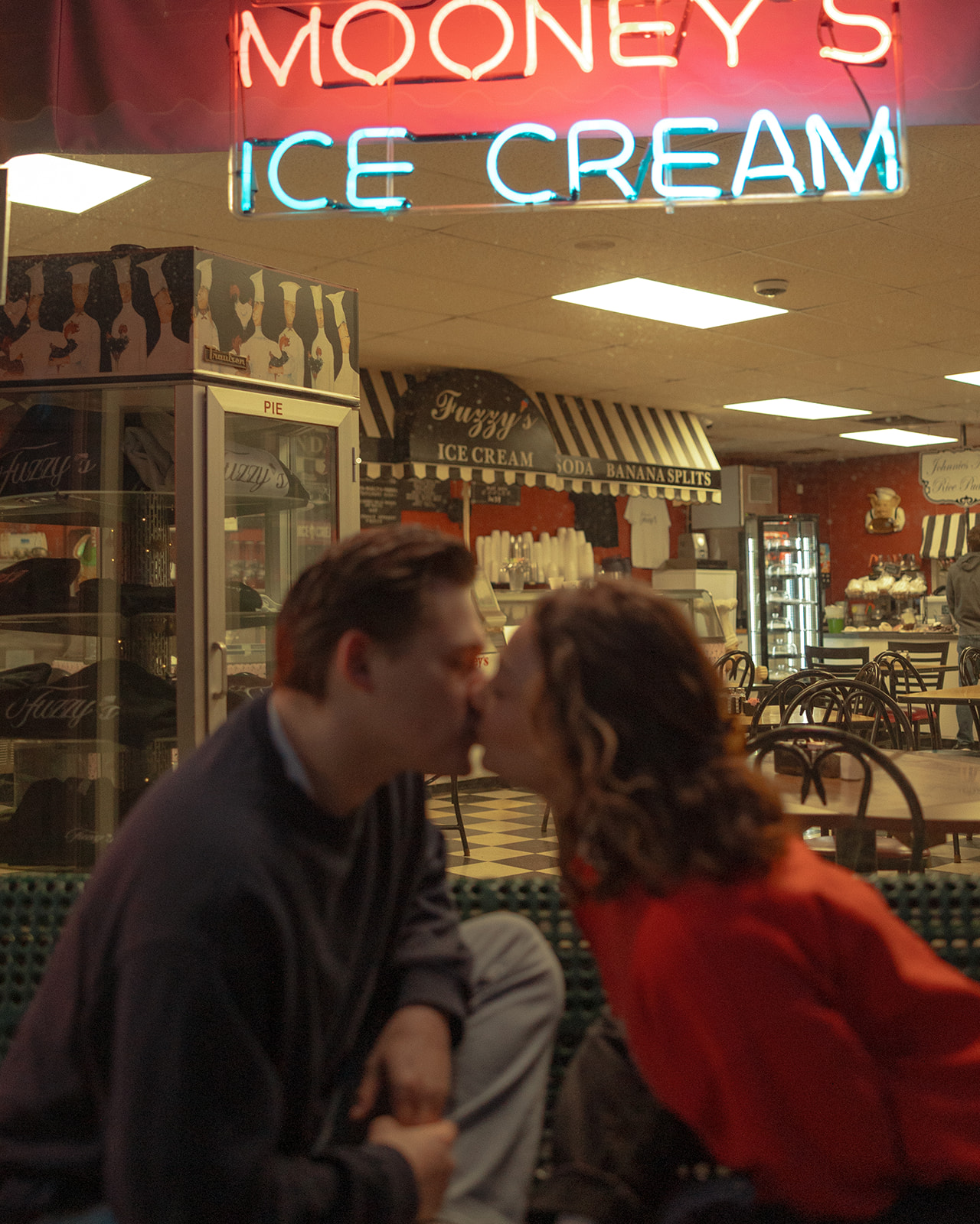 Couple kissing on a bench in Michigan for their Ice Cream Shop engagement photos