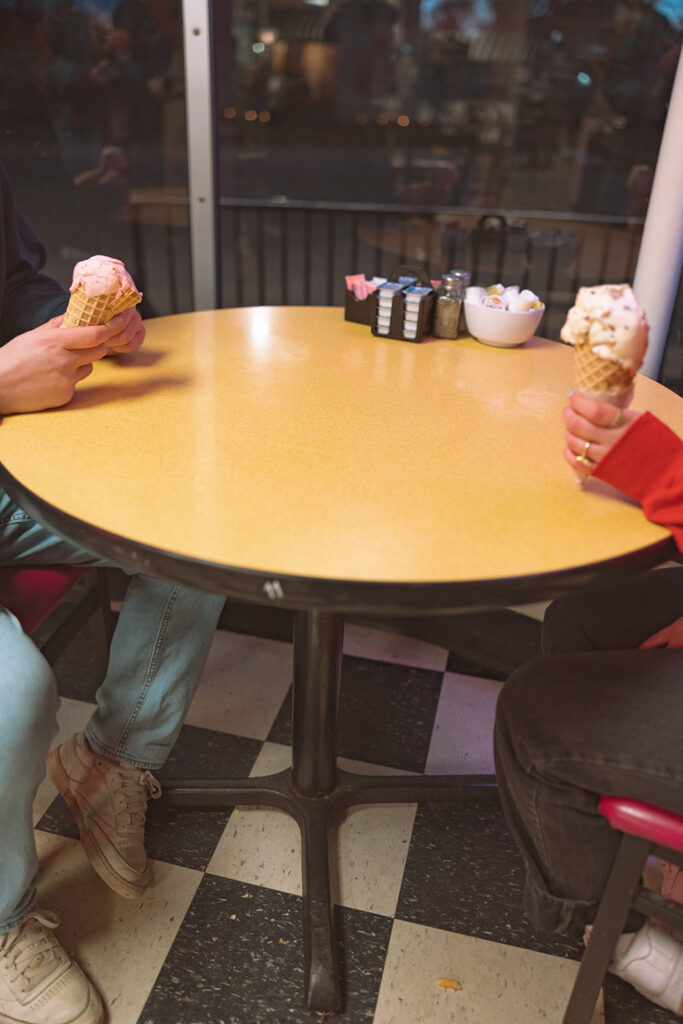 Couple sitting together at a table for their Ic Cream Shop engagement photos