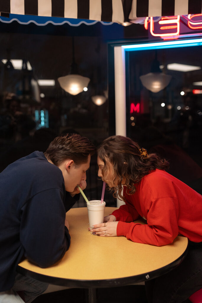 Couple drinking a milkshake during their Michigan ice cream shop engagement photos