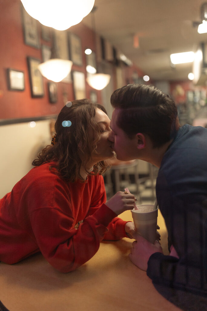 Couple kissing during their ice cream shop engagement shoot