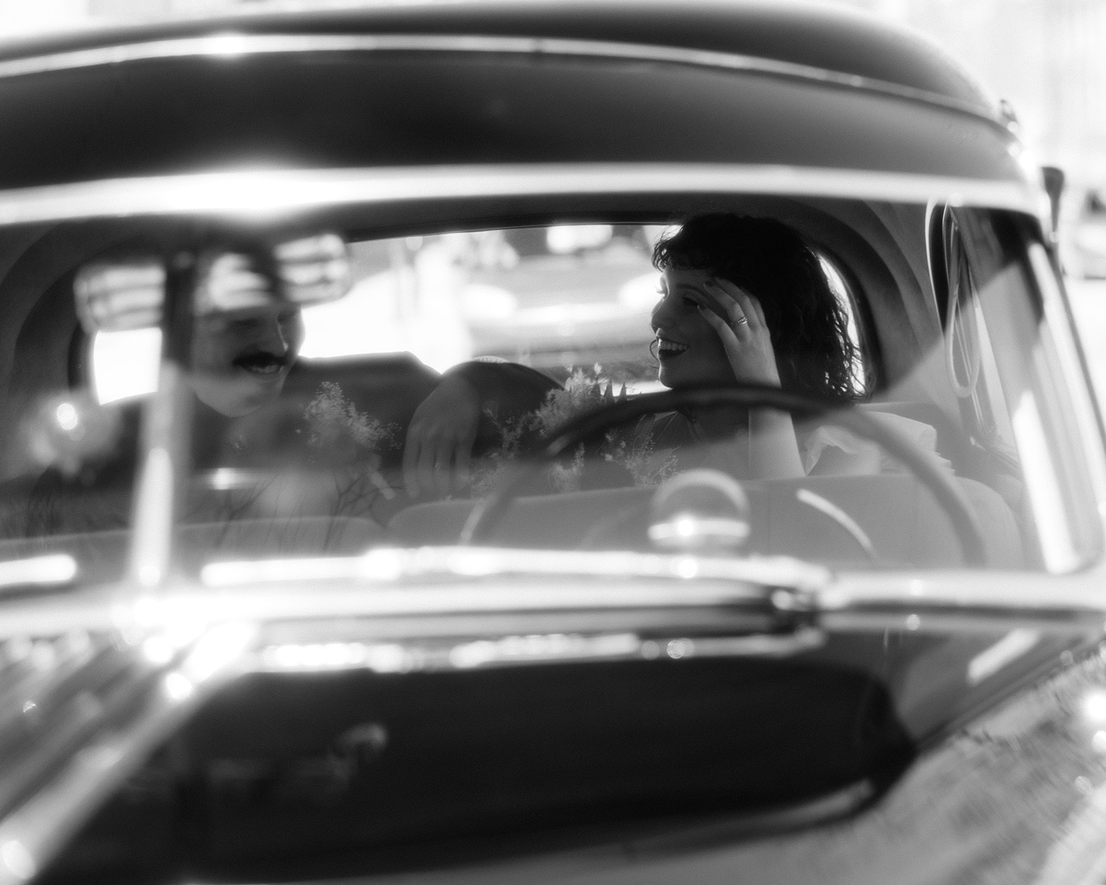A cinematic black-and-white view of the couple inside a vintage car, laughing and soaking up post-ceremony bliss during their Grand Rapids elopement.