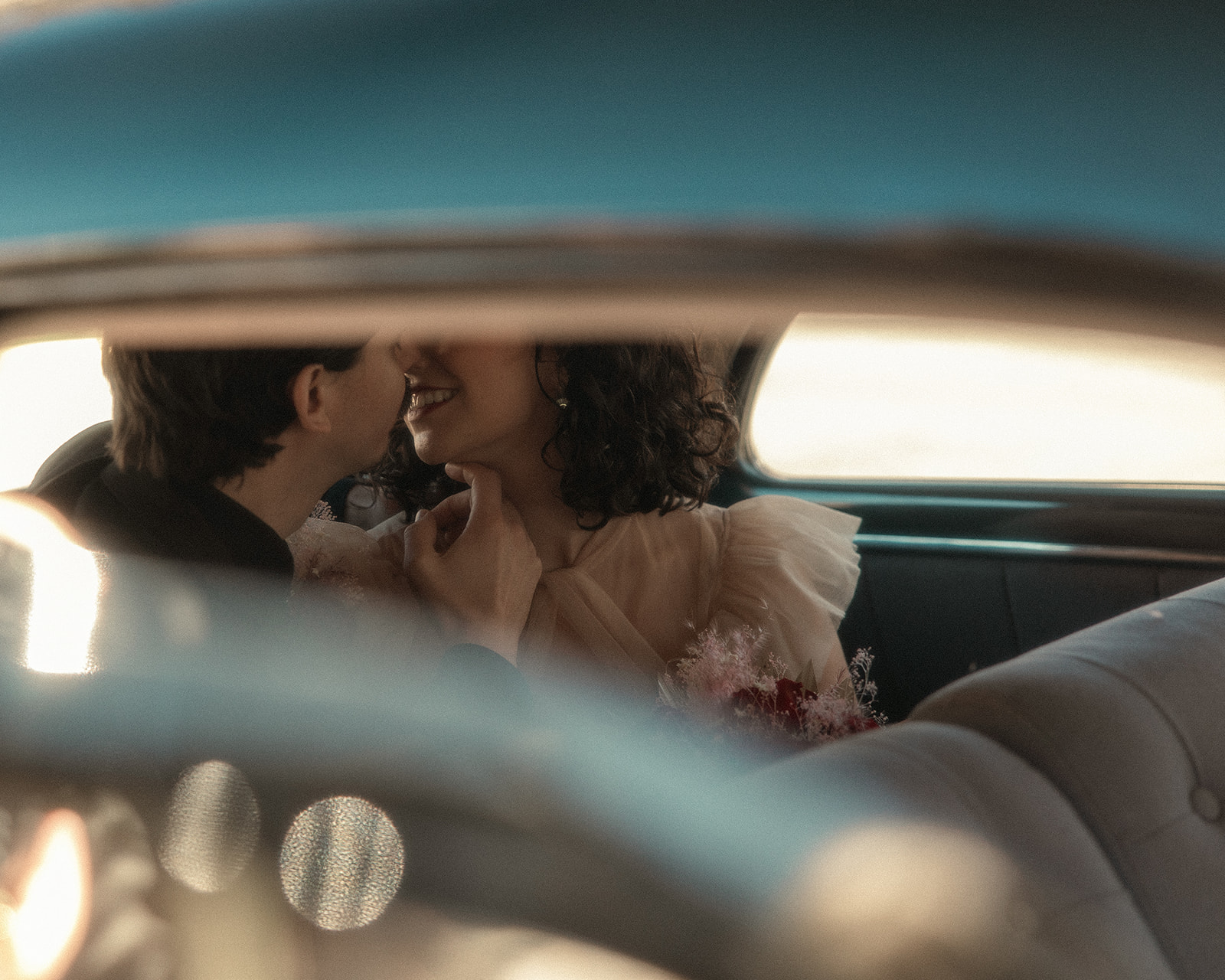 Intimate moment between bride and groom as they share a kiss in the back of a vintage getaway car after their Grand Rapids wedding ceremony.