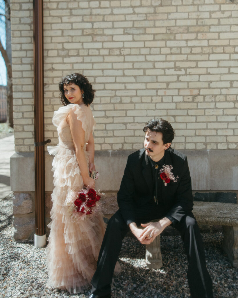 Couple sitting on stone bench outside, sharing a quiet moment during Michigan elopement