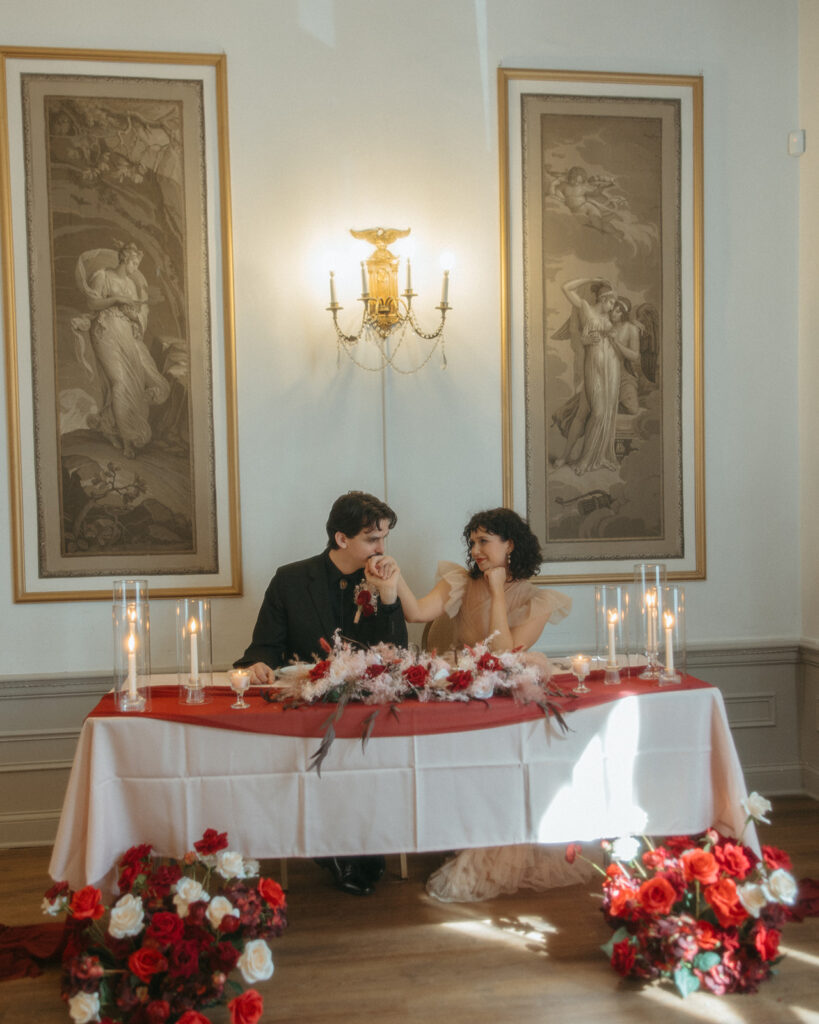 Bride and groom posing for photos at their sweethearts table