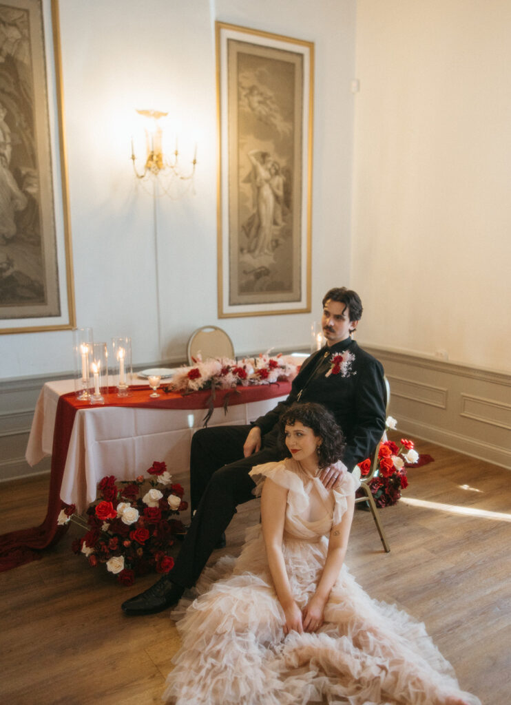 Bride and groom posing next to their intimate elopement reception sweetheart table