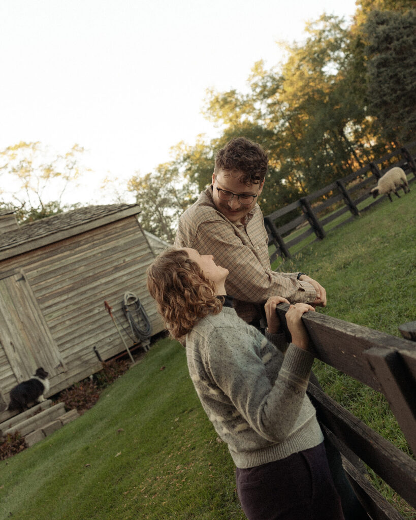 Couple leaning against their backyard fence for their Michigan engagement photos